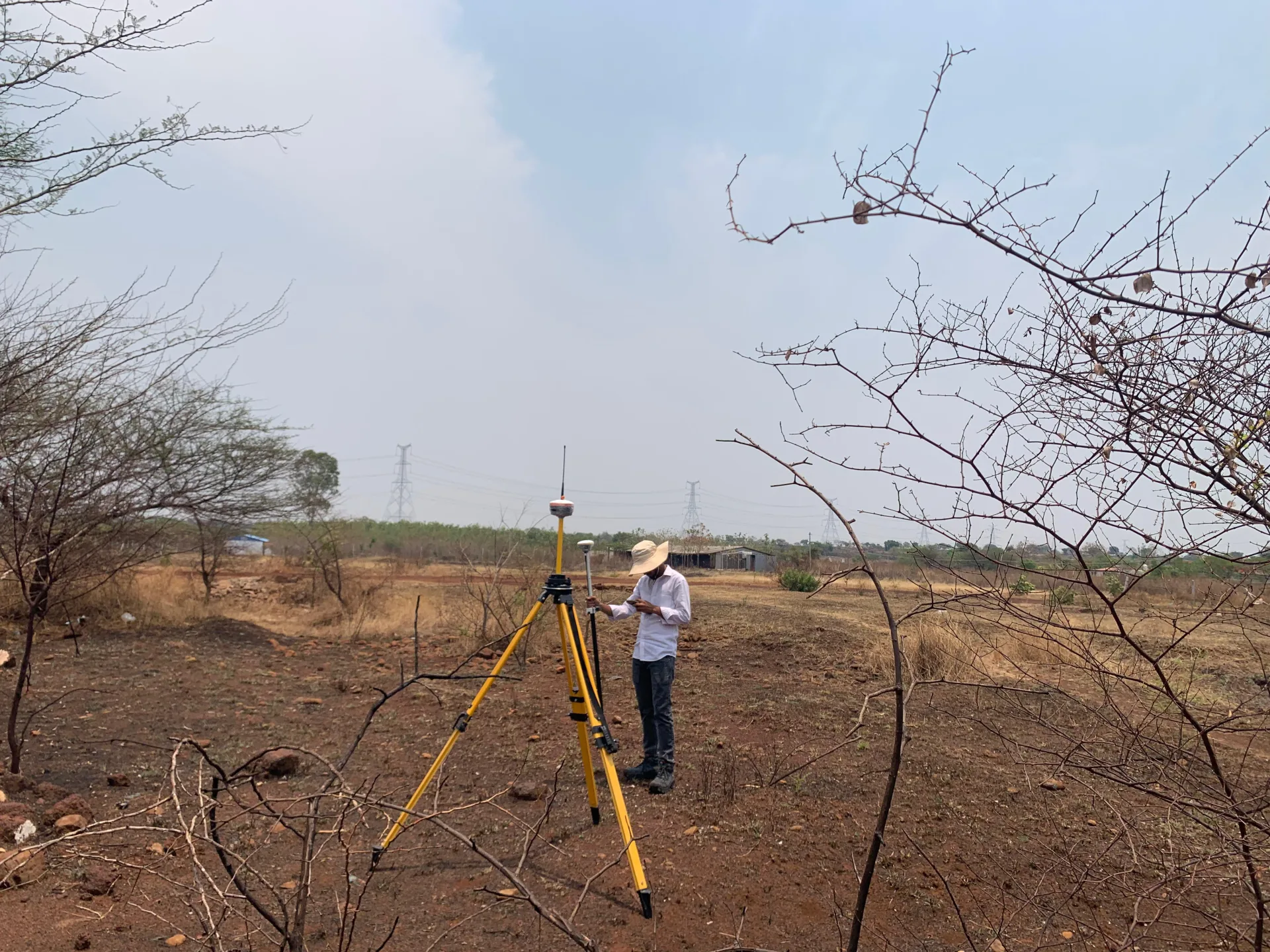 ARF GeoTech surveyor operating a total station on a cleared open plot