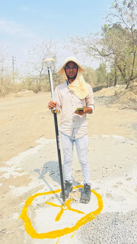 Surveyor with a GNSS rover pole over a painted control point
